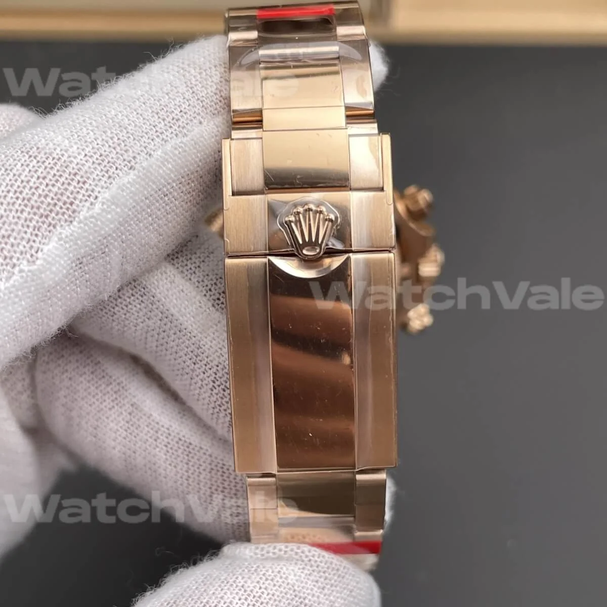 Side angle of a rose gold chronograph watch with polished Oyster-style bracelet